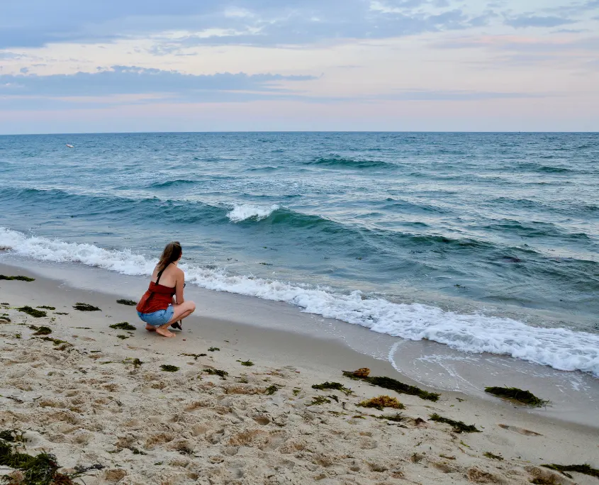 Imagen de una mujer de cuclillas frente al mar