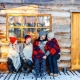 Foto de una familia sentados en un porque en una cabaña invernal