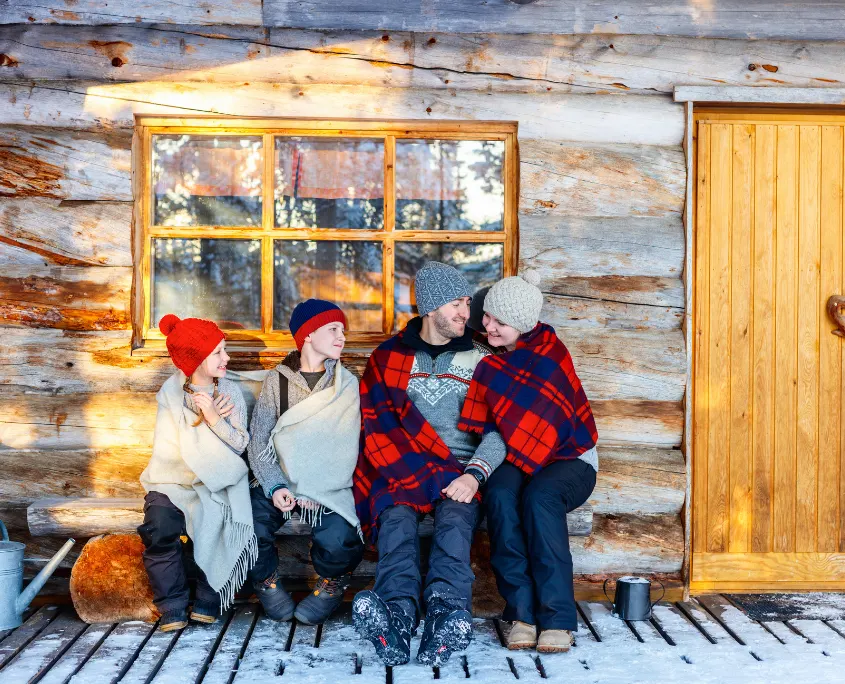 Foto de una familia sentados en un porque en una cabaña invernal