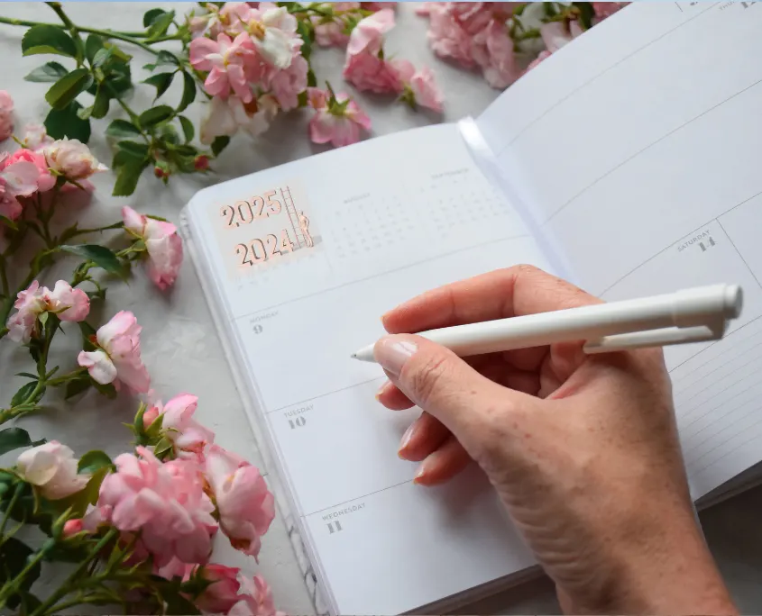 imagen de las manos de una mujer escribiendo en una agenda para 2025