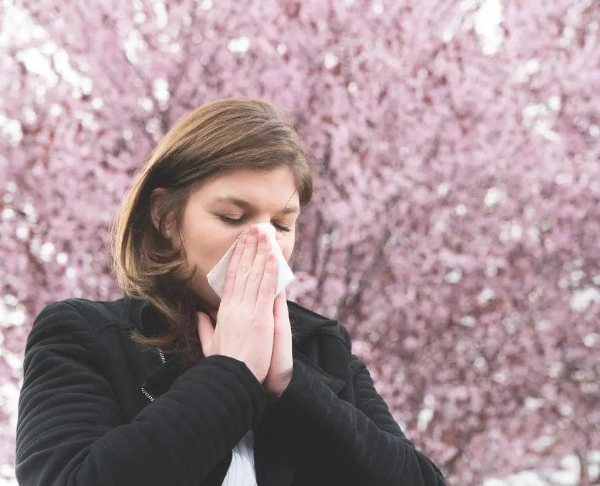 Foto de mujer con alergia sonándose la nariz con un pañuelo
