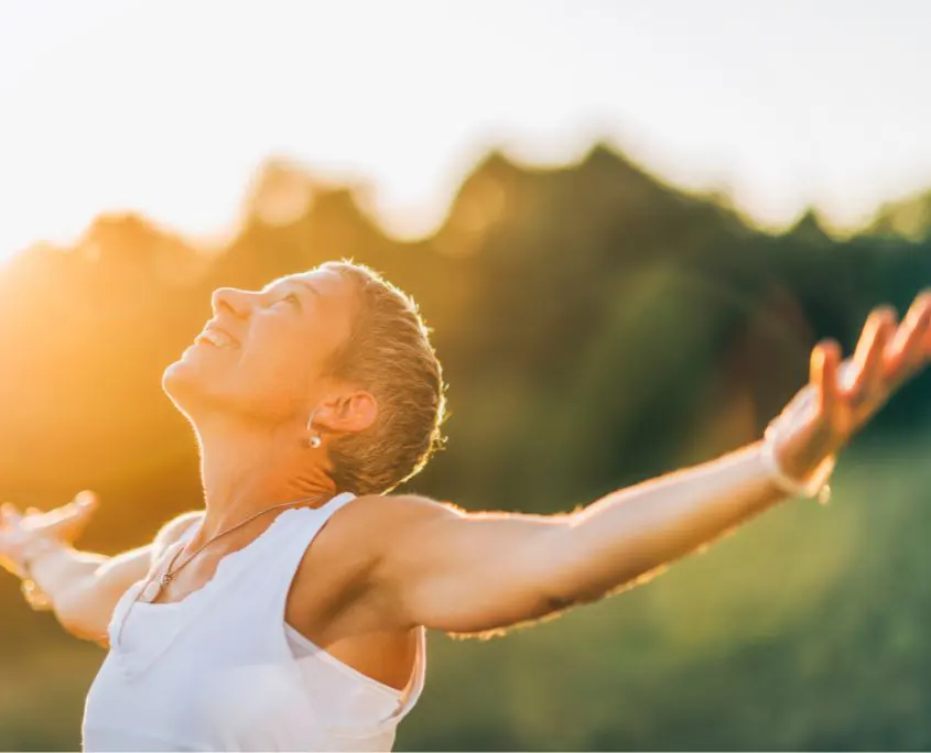 imagende mujer feliz en el campo con los brazos abiertos y con luz de atardecer